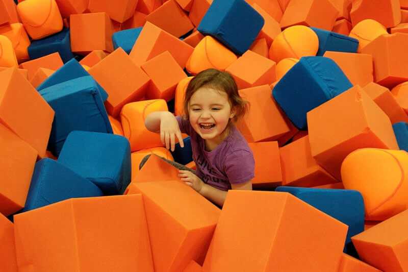 Young girl laughing after jumping into foam pit at Open Jump